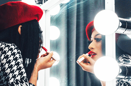 woman applying lipstick with mirror